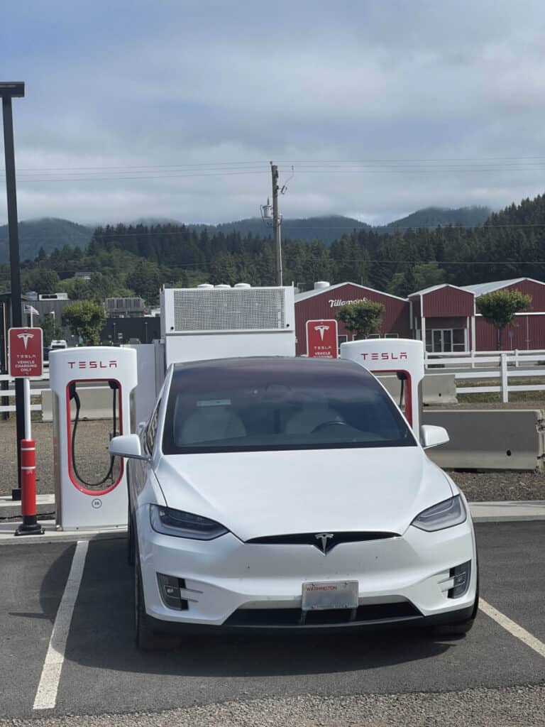 A white Tesla Model X supercharging at Tillamook, Oregon across from the Tillamook Creamery Factory